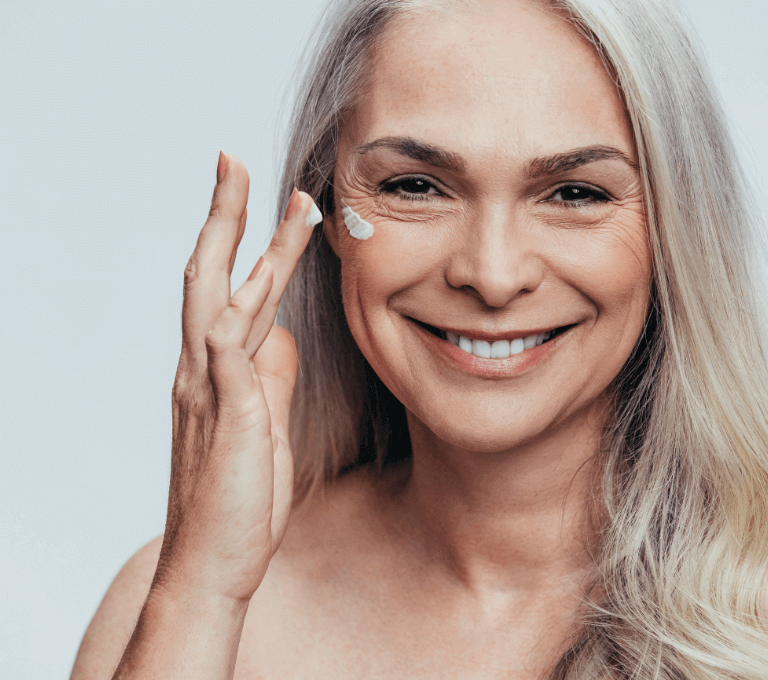 Older woman putting on anti ageing skincare to reduce fine lines